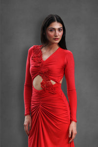 Close-up of a woman wearing an embellished red dress with floral details against a gray background.