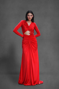 Model wearing The Ember Gown in cherry red with embellished bodice and front cut-out on a gray background.